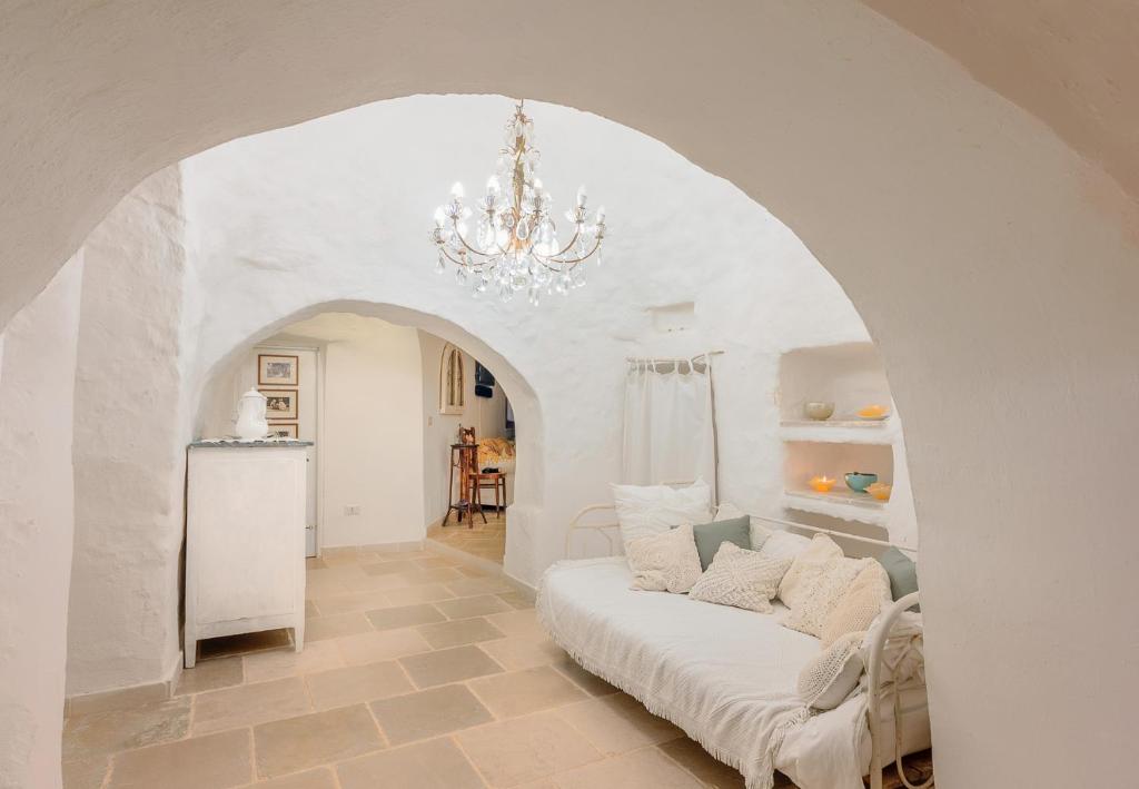 d'un salon avec un canapé blanc et un lustre. dans l'établissement Trulli La Formosa - The Fab Stay, à Ostuni