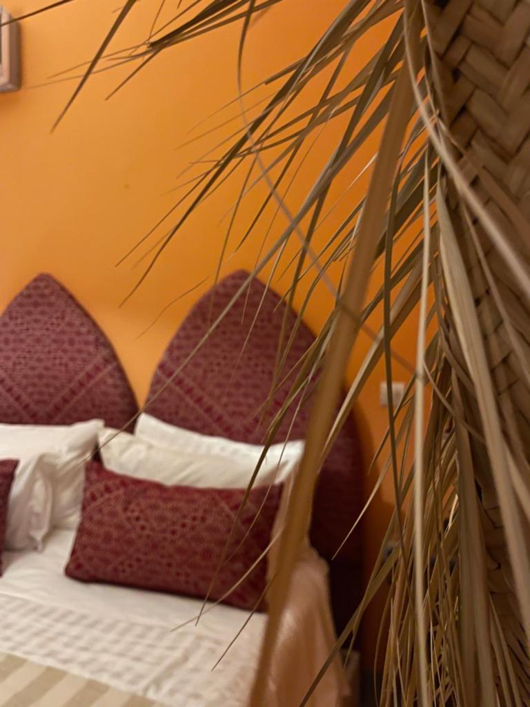 un lit avec des oreillers rouges et blancs et une plante dans l'établissement RIAD DAR NAOMI, à Marrakech