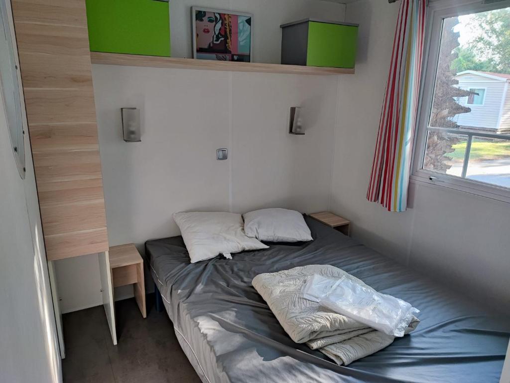 - un petit lit dans une petite chambre avec fenêtre dans l'établissement Sun Sea camping le Bosc, à Saint-Cyprien