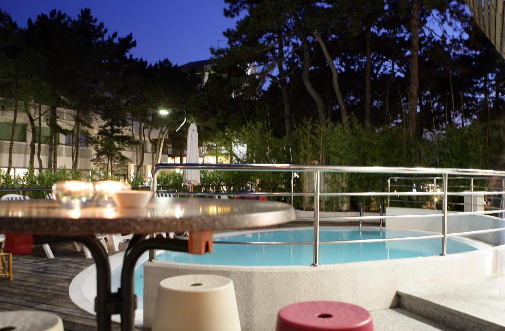 un patio avec une table et une piscine dans l'établissement Hotel Anapaya, à Lignano Sabbiadoro
