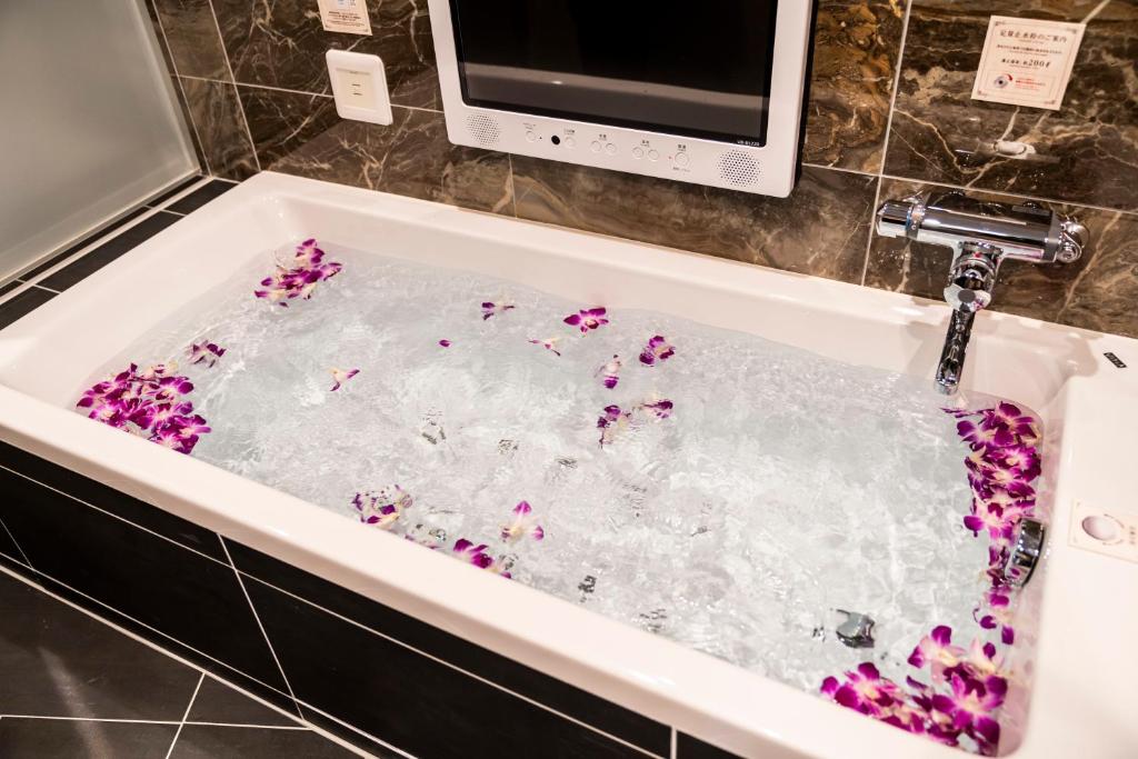 une baignoire remplie d'eau et de fleurs violettes dans l'établissement Hotel Bali An Resort Shinjuku Forest, à Tokyo