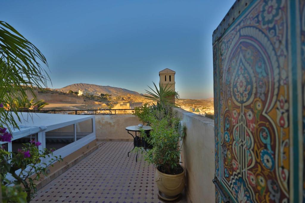 d'un balcon avec des plantes et une tour d'horloge au loin. dans l'établissement Riad Les Idrissides Chez LEA, à Fès