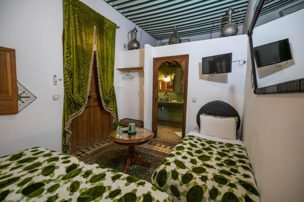 une chambre avec un lit, une table et un miroir dans l'établissement Riad Les Idrissides Chez LEA, à Fès