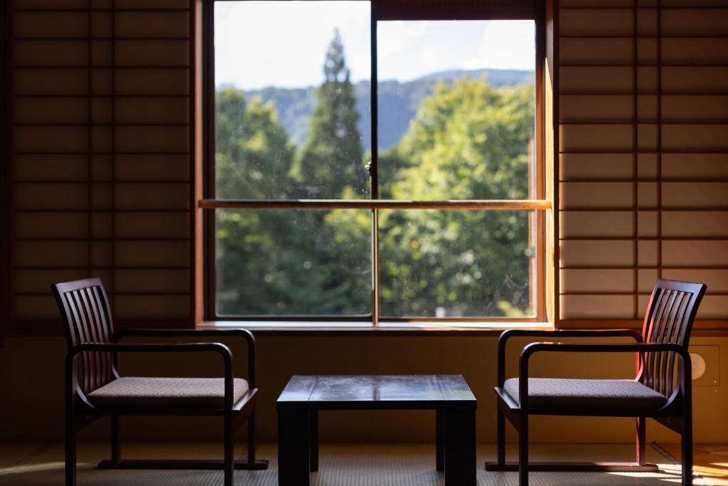 deux chaises et une table devant une fenêtre dans l'établissement KAMENOI HOTEL Tazawako, à Senboku 37 autres photos