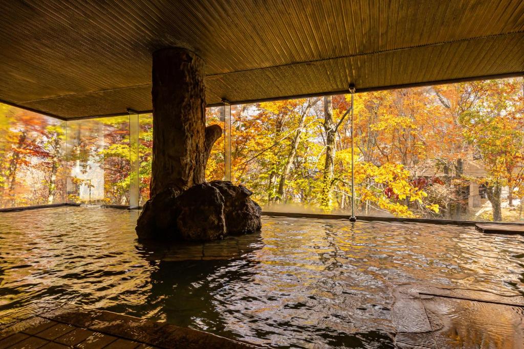 un arbre dans l'eau sous un pont dans l'établissement KAMENOI HOTEL Tazawako, à Senboku