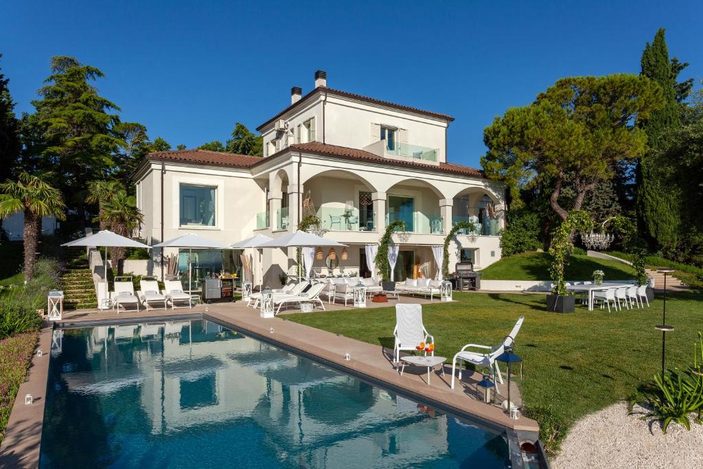 une grande maison avec une piscine devant dans l'établissement Villa Belvedere, à Bertinoro