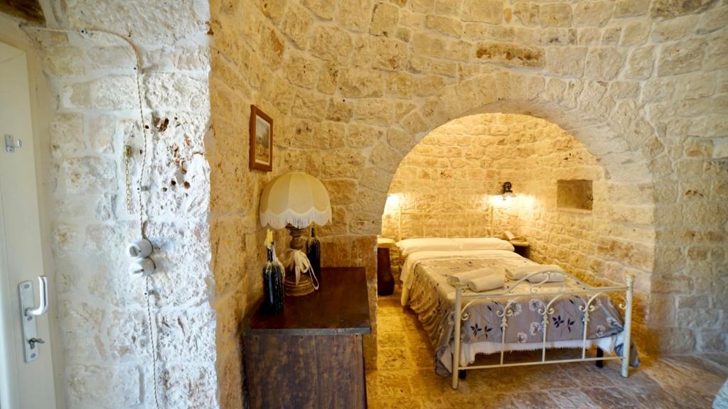 une chambre avec un lit dans un mur de pierre dans l'établissement Dimora Trullivo, Charming House, à Castellana Grotte