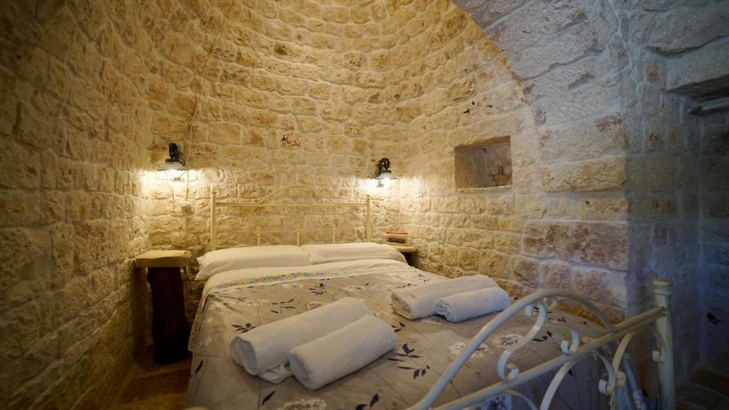 une chambre avec un lit dans un mur de pierre dans l'établissement Dimora Trullivo, Charming House, à Castellana Grotte
