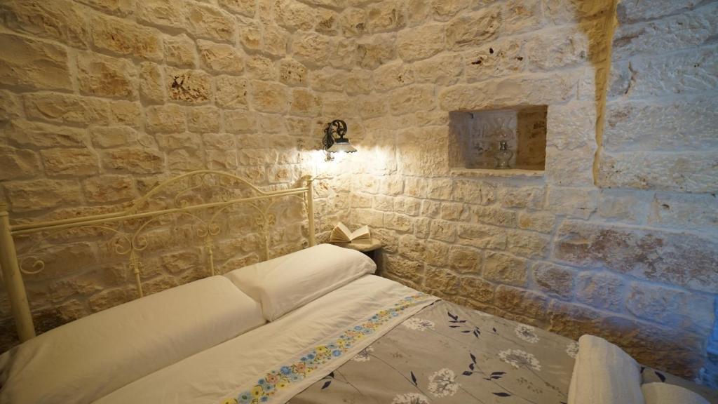 un lit dans une chambre avec un mur en pierre dans l'établissement Dimora Trullivo, Charming House, à Castellana Grotte 63 autres photos
