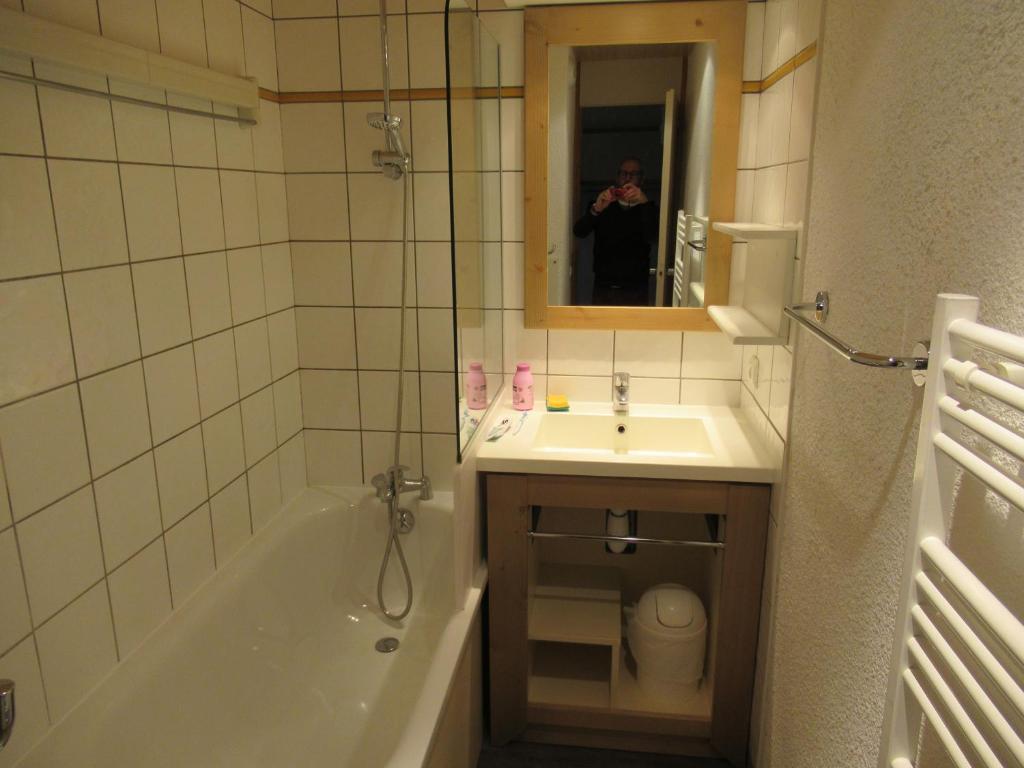 une personne prenant une photo d'une salle de bains avec baignoire et lavabo dans l'établissement Appartement 644 au pied des pistes de Belle Plagne, à La Plagne Tarentaise