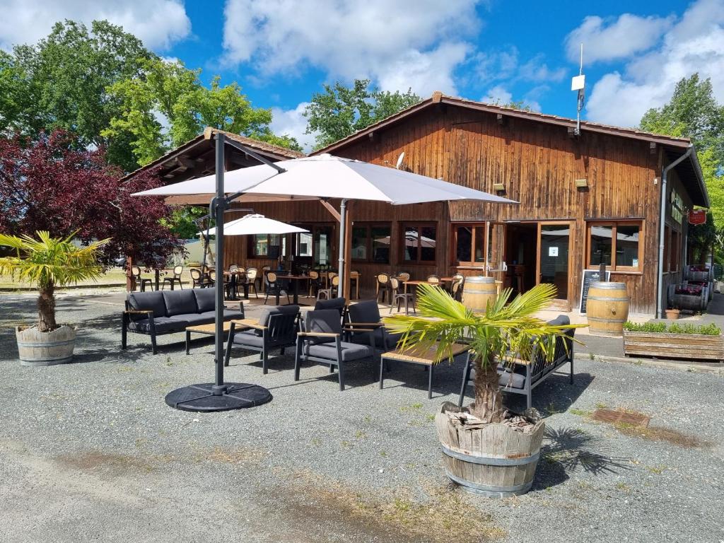 un restaurant avec des chaises et des parasols en face d'un bâtiment dans l'établissement Mobil Home XXL 4 chambres - Camping du Vieux Moulin, à Vensac