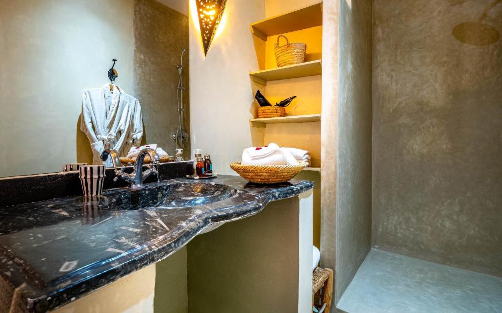 La salle de bains est pourvue d'un lavabo avec un costume sur mannequin. dans l'établissement Riad L'orange Bleue, à Marrakech