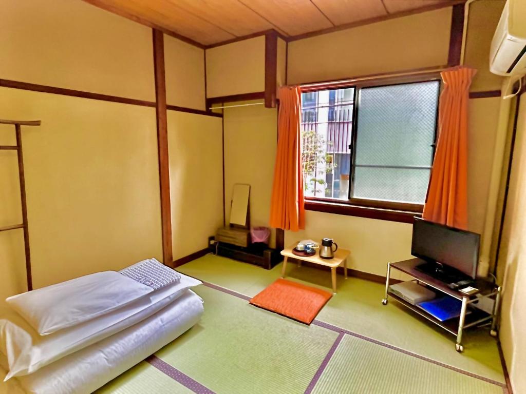 une chambre avec un lit, une télévision et une fenêtre dans l'établissement Yamamoto Ryokan, à Fukuoka
