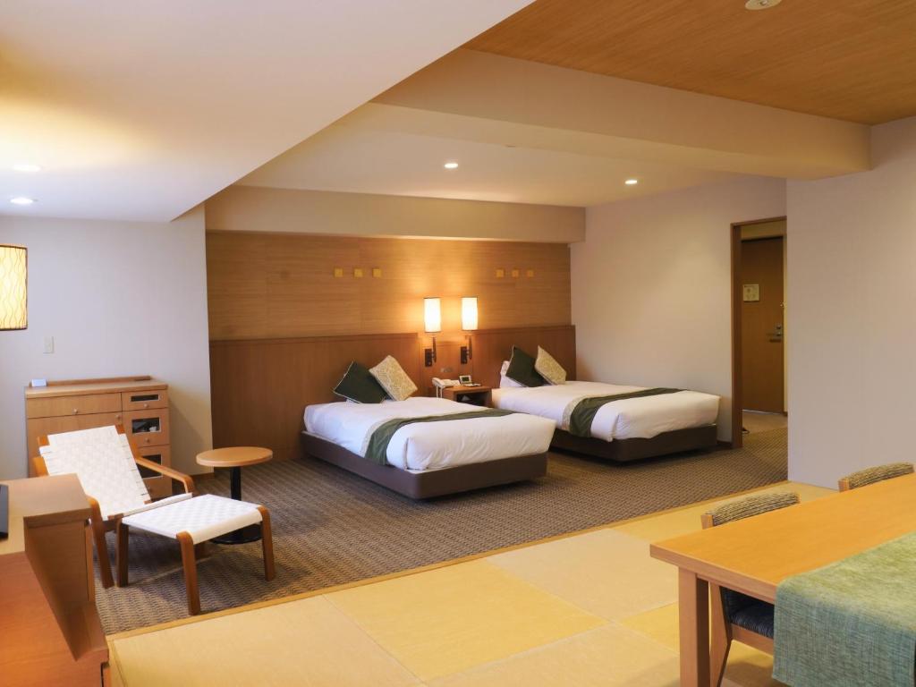 une chambre d'hôtel avec deux lits et une table dans l'établissement Yumoto Noboribetsu, à Noboribetsu