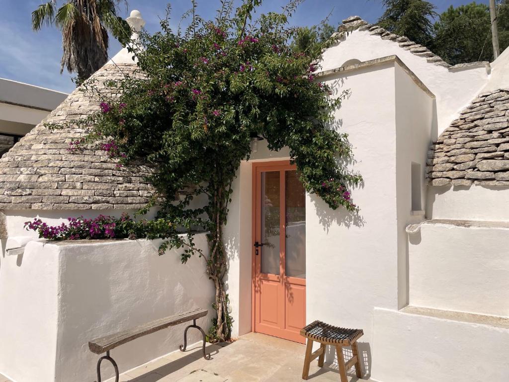 une maison blanche avec une porte rouge et des fleurs dans l'établissement Trullo Panna Fragola - Exclusive four bedroom Villa & Private pool, à Martina Franca