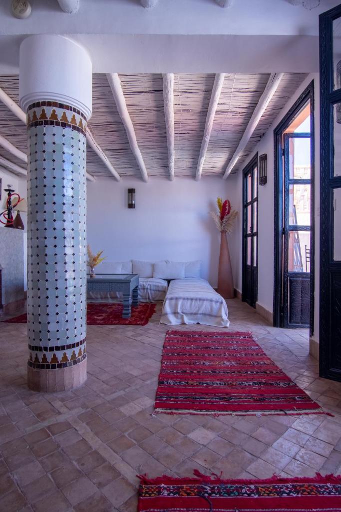 Cette grande chambre comprend un lit et une colonne. dans l'établissement Riad Hugo, à Marrakech