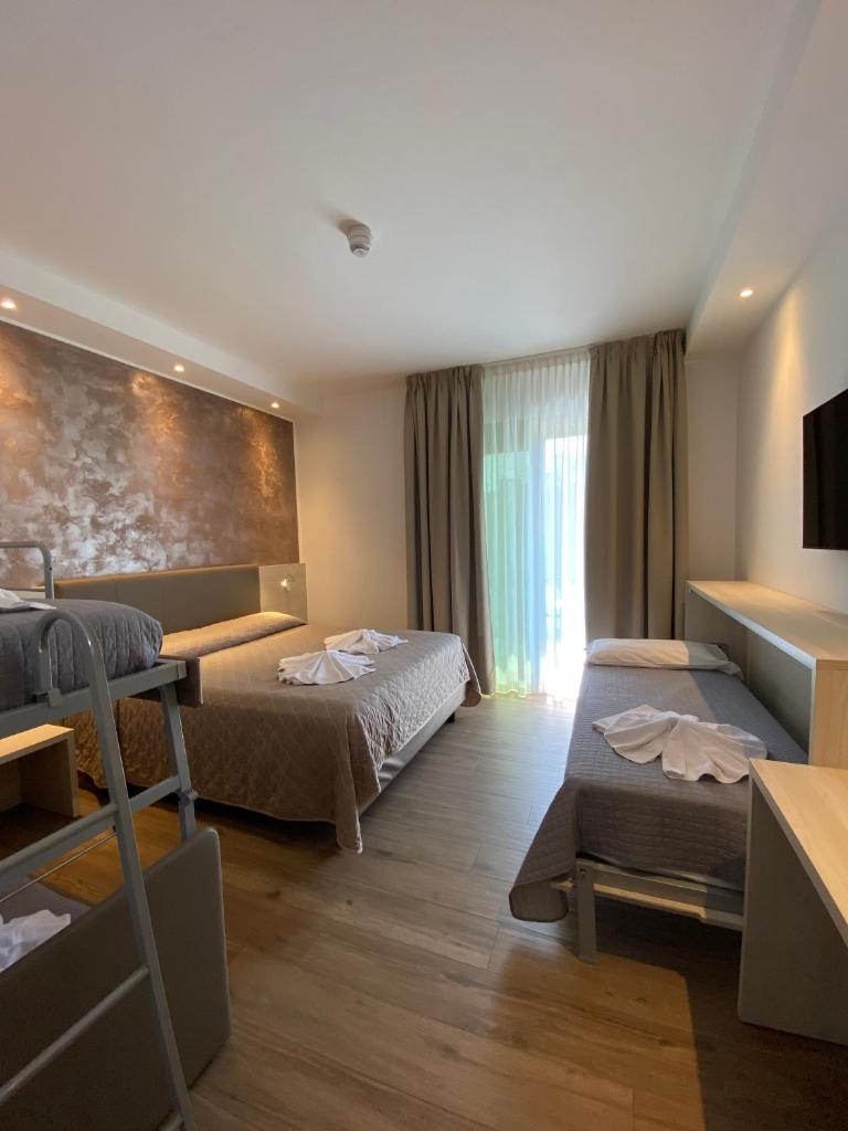 une chambre d'hôtel avec deux lits et une grande fenêtre dans l'établissement Hotel ALDEBARAN, à Lido di Jesolo