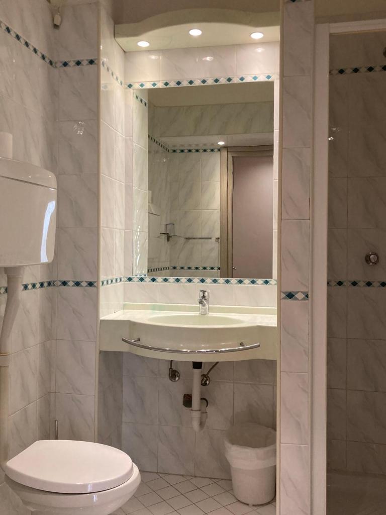 une salle de bain avec un lavabo, des toilettes et un miroir dans l'établissement Hotel Villa Itala, à Rimini