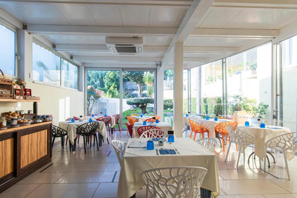 un restaurant avec des tables, des chaises et des fenêtres dans l'établissement Marina 10 Design Hotel & SPA, à Ischia