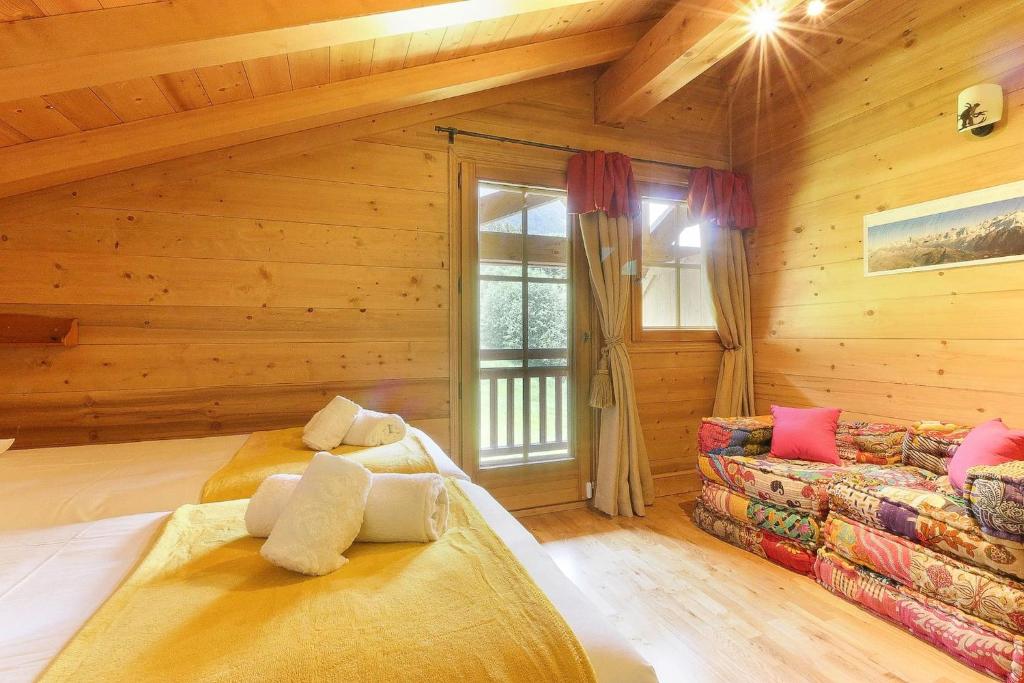 - une chambre en rondins avec 2 lits et un canapé dans l'établissement Maison Neuve - Grand appartement- Terrasse - Vue sur la vallée du Mont-Blanc, aux Houches