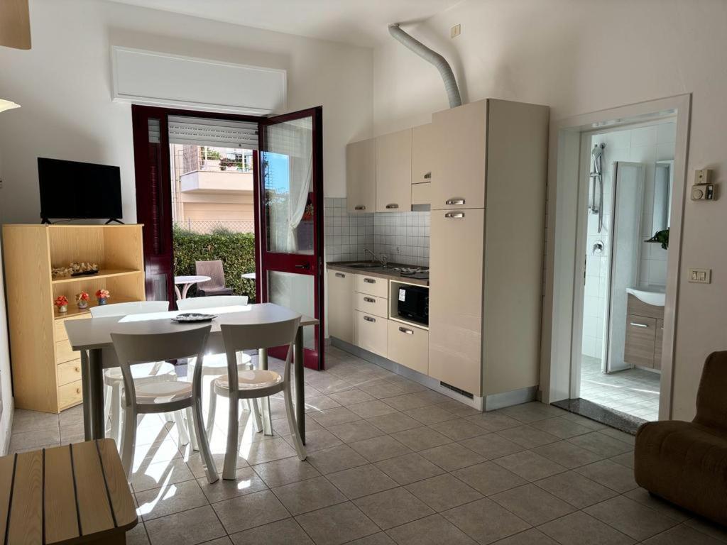 - une cuisine avec une table et des chaises blanches dans la chambre dans l'établissement Residence Summer Dream, à Cervia
