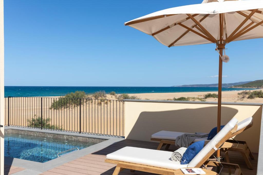 un patio avec un parasol et une piscine dans l'établissement Hotel Le Dune Piscinas, à Ingurtosu