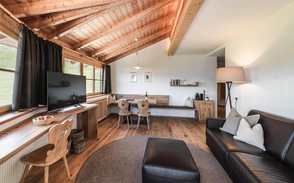 Elle comprend un salon avec un canapé et un bureau avec une télévision. dans l'établissement Exclusive Chalet Grumer 700 sqm, à Soprabolzano