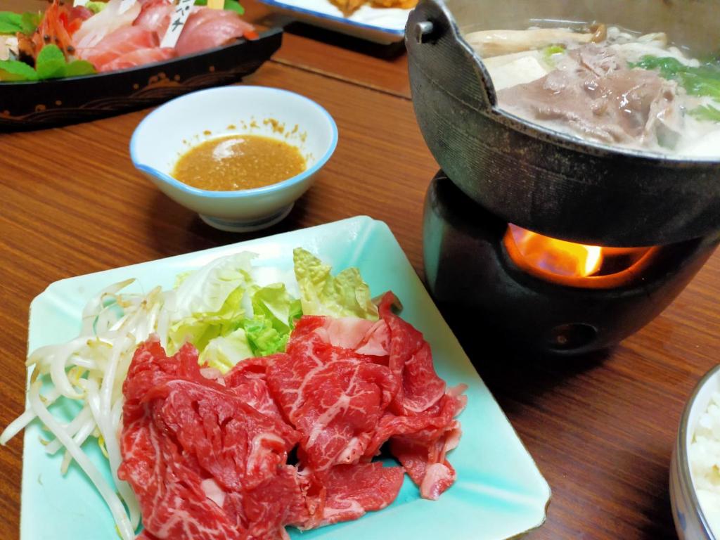 une assiette de nourriture avec de la viande et de la salade sur une table dans l'établissement Sado Ryosou Minato, à Sado 18 autres photos