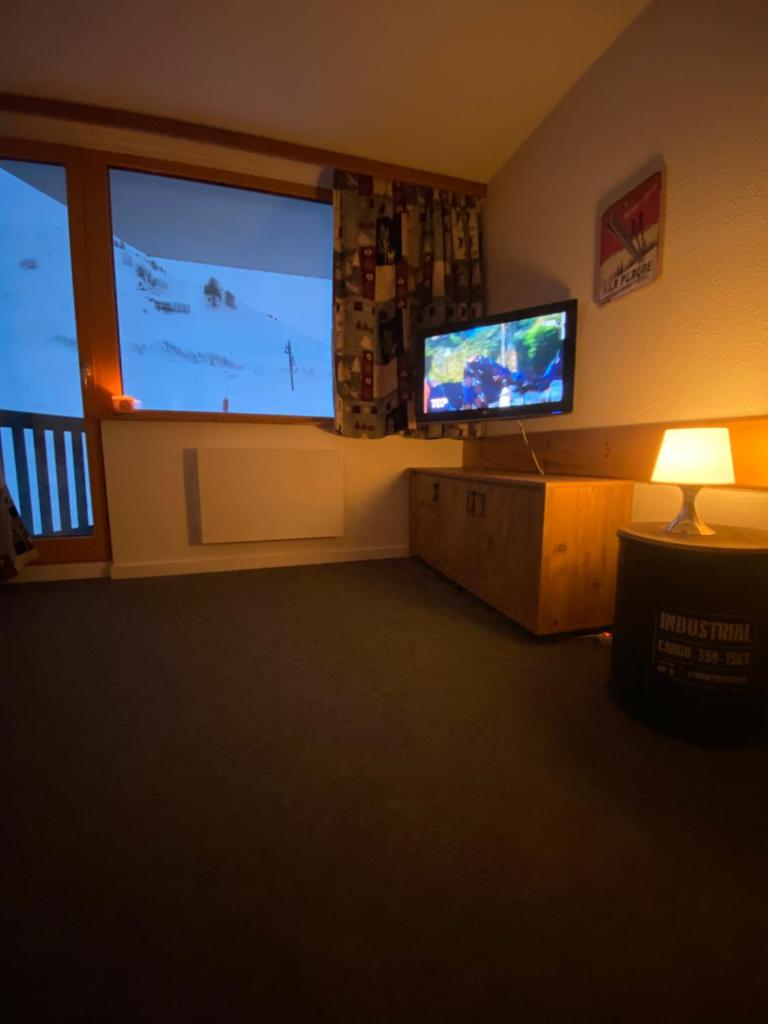 un salon avec une télévision et une grande fenêtre dans l'établissement Studio de la Marmotte - Aime 2000, à Aime La Plagne