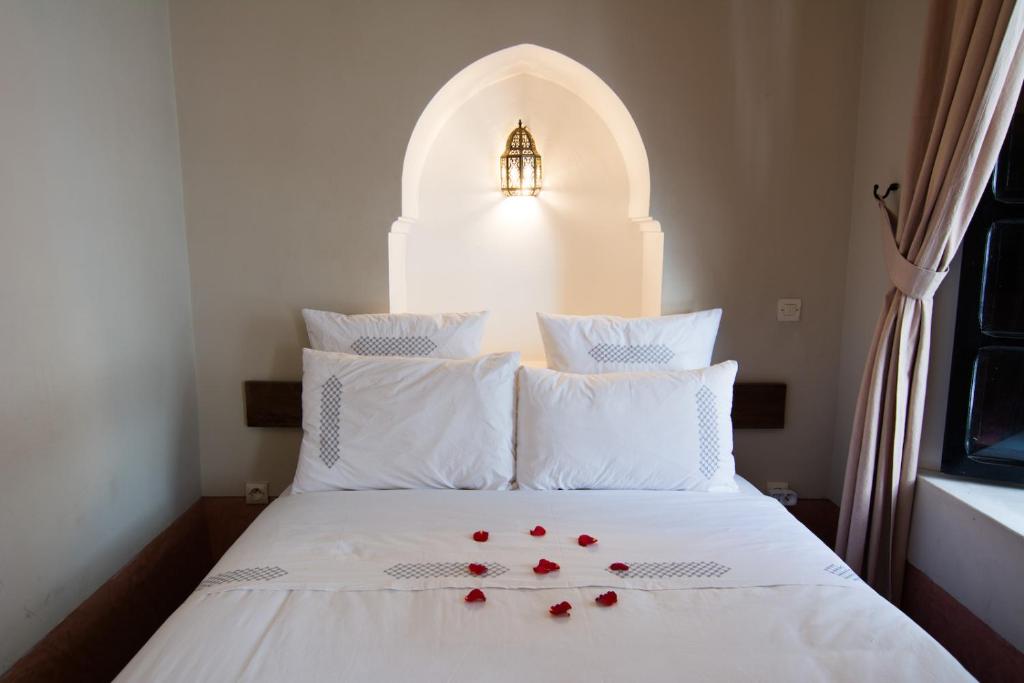 une chambre avec un lit avec des fleurs rouges dessus dans l'établissement Riad Dar El Gnaouia, à Marrakech