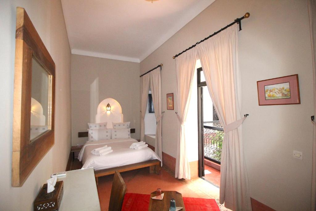 une chambre avec un lit et une grande fenêtre dans l'établissement Riad Dar El Gnaouia, à Marrakech