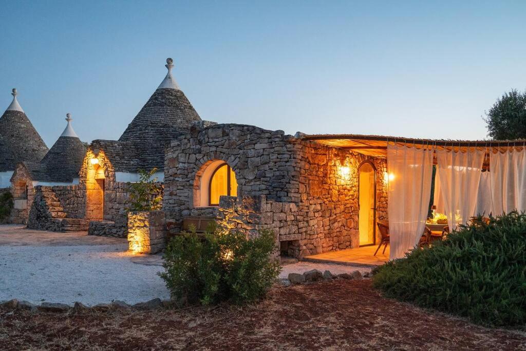 une maison en pierre avec des lumières devant elle dans l'établissement Trullo Elaia - Dimora di charme in Valle d'Itria con piscina, à Ceglie Messapica