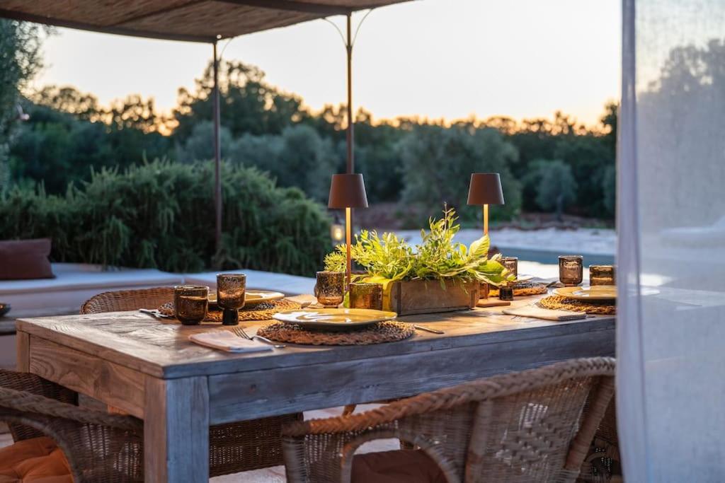 une table en bois avec des assiettes de nourriture sur une terrasse dans l'établissement Trullo Elaia - Dimora di charme in Valle d'Itria con piscina, à Ceglie Messapica