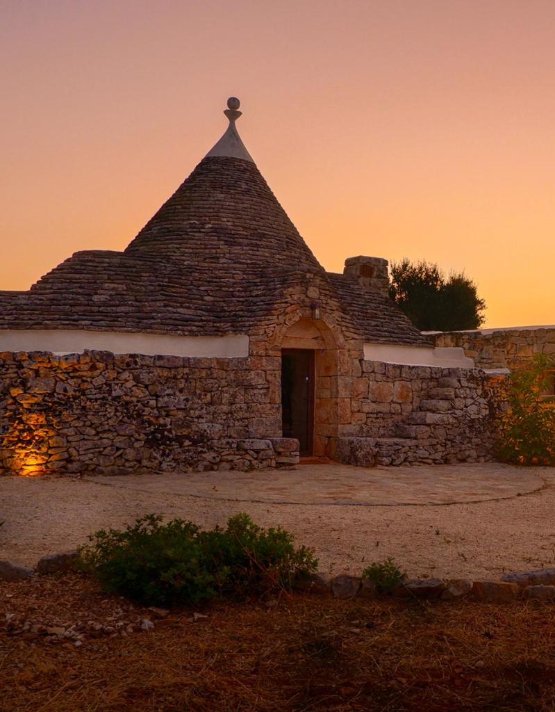un vieux bâtiment en pierre avec un sommet pyramidal dans l'établissement Trullo Elaia - Dimora di charme in Valle d'Itria con piscina, à Ceglie Messapica