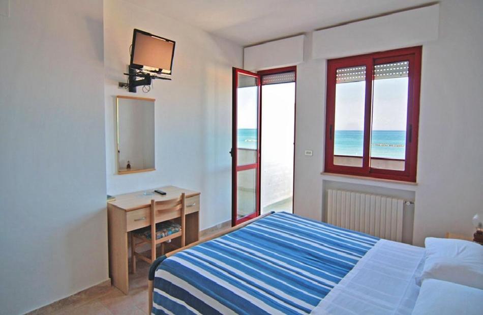 une chambre avec un lit, un bureau et des fenêtres dans l'établissement Hotel Palmarosa, à Roseto degli Abruzzi