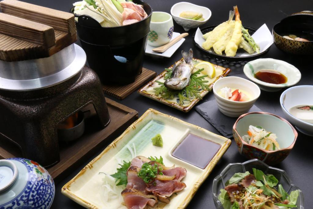 une table sur laquelle sont posées des assiettes de nourriture et d'autres plats dans l'établissement Minshuku Shiroyama, à Taketa