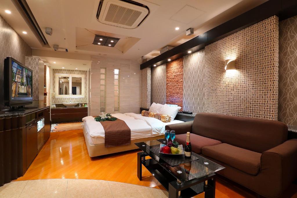 Cette chambre comprend un lit, un canapé et une télévision. dans l'établissement Hotel AXIS -アクシス-, à Osaka