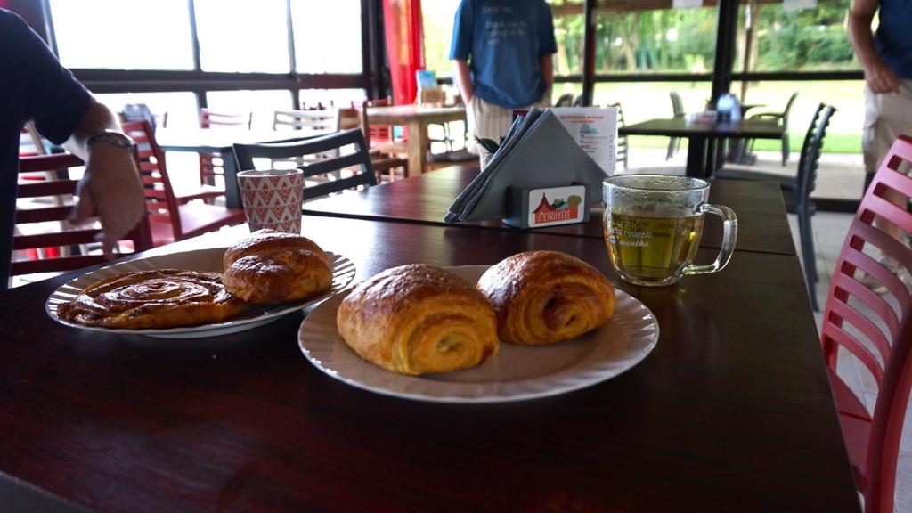 - une table avec deux assiettes de pâtisseries et un verre de bière dans l'établissement Camping L'Etruyere, à La Tardière