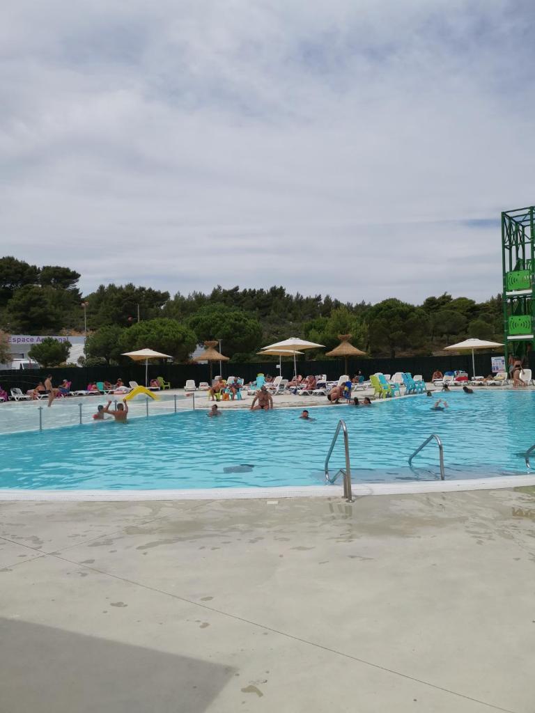 une grande piscine avec des gens dans l'eau dans l'établissement Mobil home climatisé chez Mickaël et Laëtitia, à Narbonne