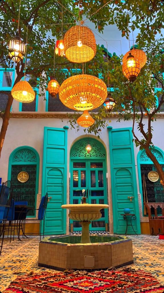 un bâtiment avec des portes bleues et une fontaine éclairée dans l'établissement Riad Al Nour, à Marrakech