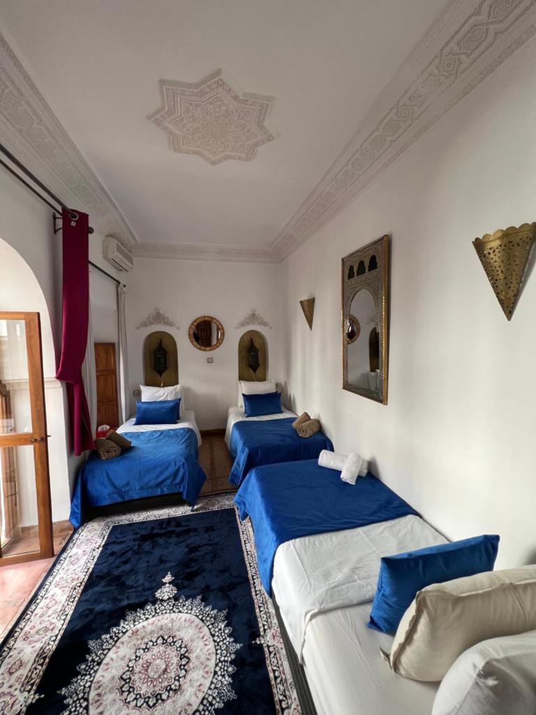 Cette chambre comprend 4 lits avec des draps bleus. dans l'établissement Riad Villa El Arsa, à Marrakech