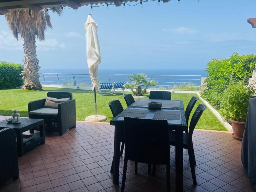 un patio avec une table et des chaises et l'océan dans l'établissement Villa Palummo - Stunning Sea View Zambrone, Calabria, à Zambrone