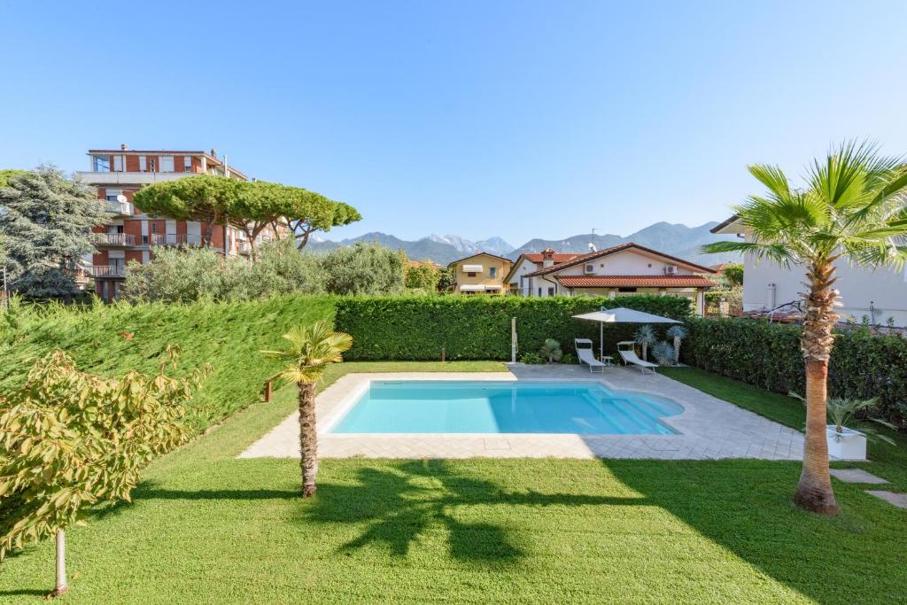 une piscine dans une cour avec des palmiers dans l'établissement Villa Fiumetto by Mmega, à Querceta