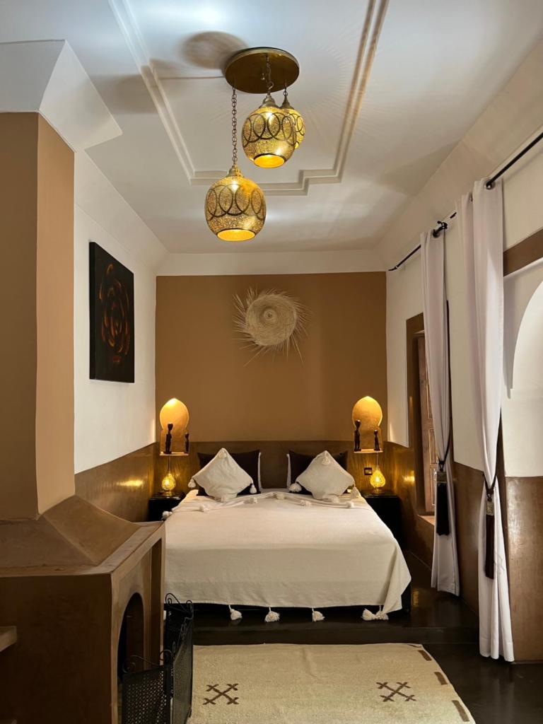 une chambre avec un lit et un lustre dans l'établissement Riad Des Arts, à Marrakech