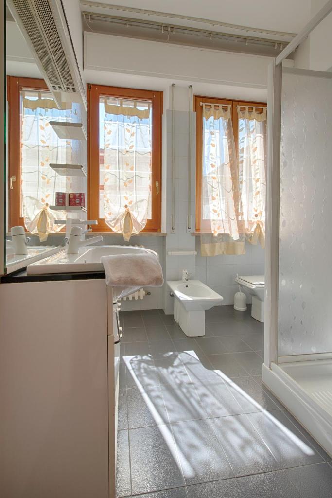 une salle de bain avec un lavabo et des toilettes et des fenêtres dans l'établissement Residence Palazzo Gasparroni, à Tortoreto Lido