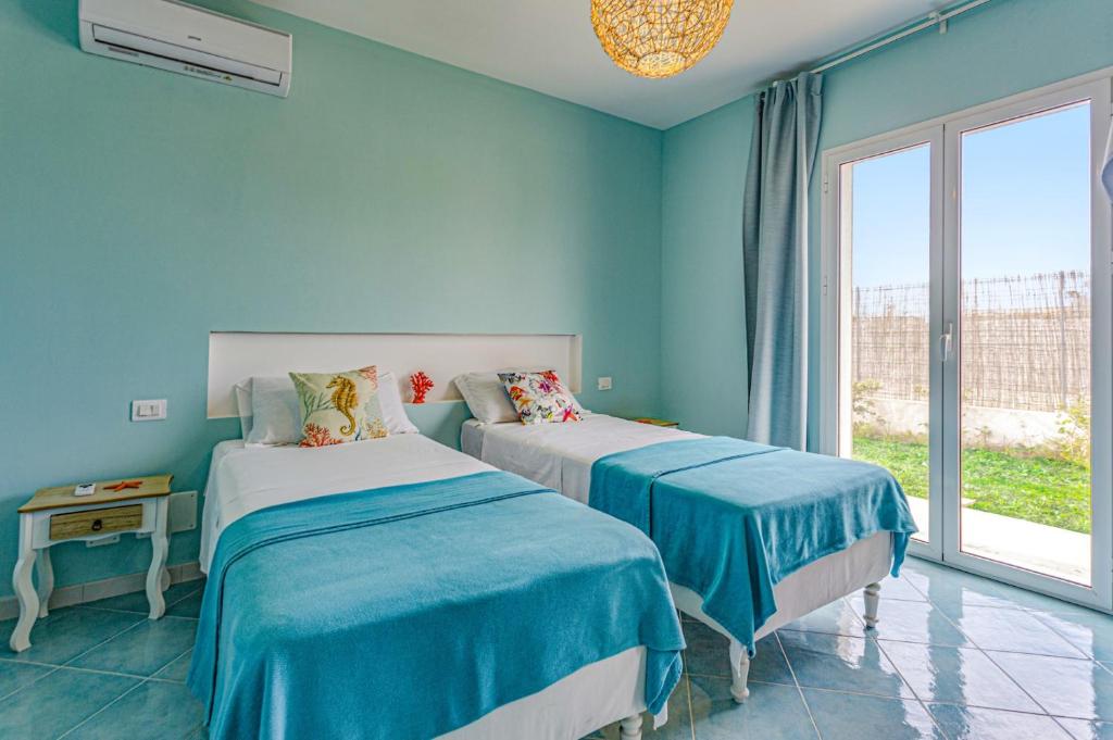 Cette chambre comprend 2 lits dans une chambre dotée de murs bleus et d'une fenêtre. dans l'établissement Villa Arancio by Villa Plus, à Santa Maria Del Focallo