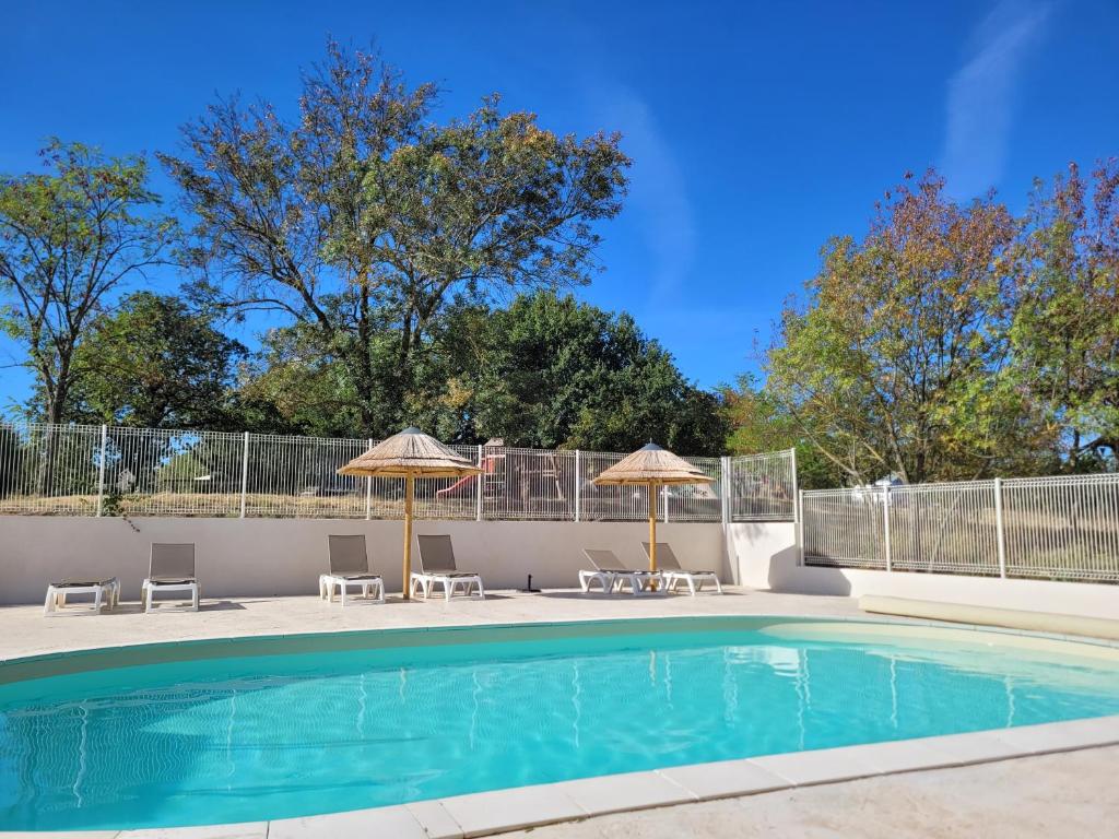 - une piscine avec deux parasols et des chaises dans l'établissement Le Mas Cauvy, à Saint-Christol-lès-Alès