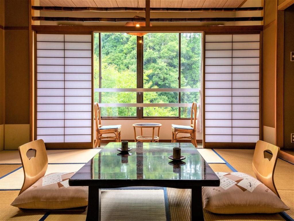 une pièce avec une table et des chaises et une grande fenêtre dans l'établissement 秘境のおやど 龍峡亭　HIKYOUNOOYADO RYUKYOUTEI, à Tokimata