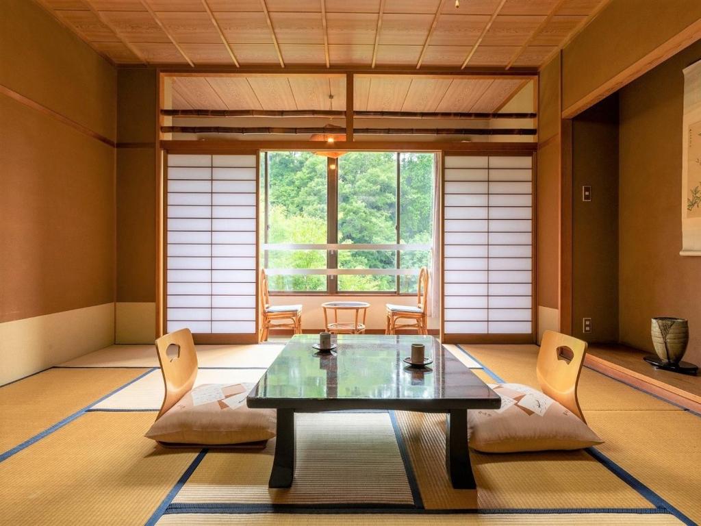 une pièce avec une table et des chaises et une grande fenêtre dans l'établissement 秘境のおやど 龍峡亭　HIKYOUNOOYADO RYUKYOUTEI, à Tokimata