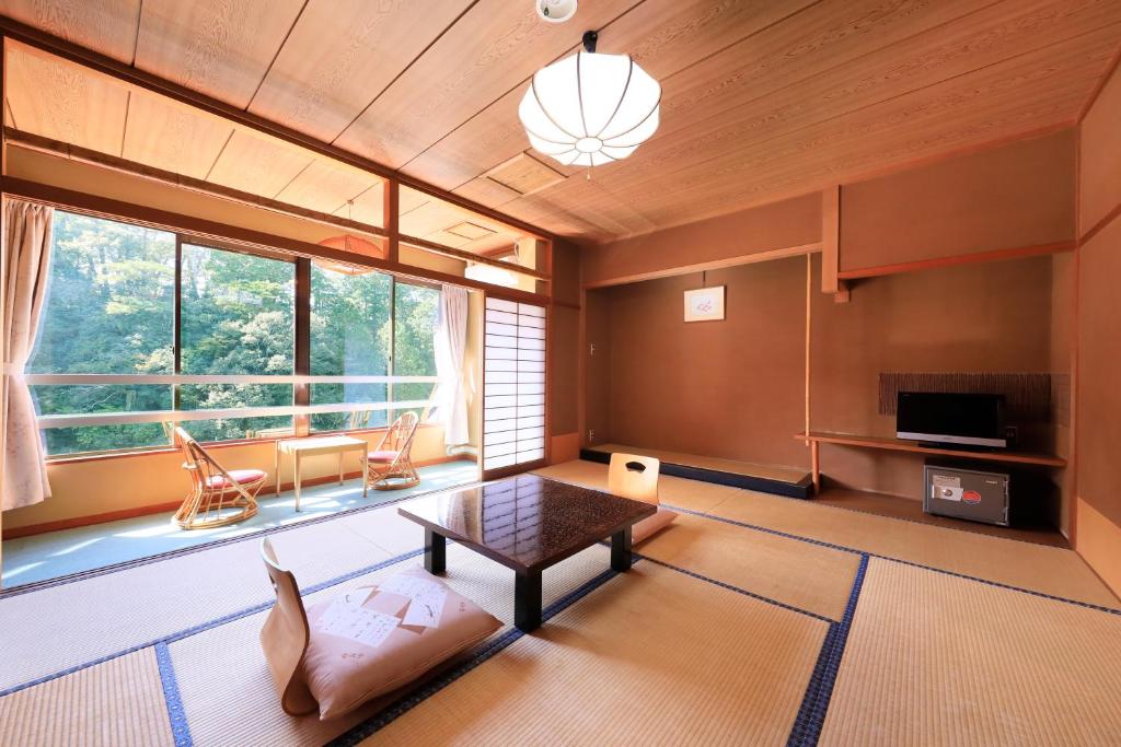 un salon avec une table basse et une grande fenêtre dans l'établissement 秘境のおやど 龍峡亭　HIKYOUNOOYADO RYUKYOUTEI, à Tokimata 20 autres photos